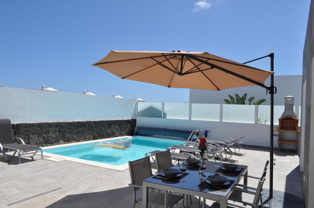 een tafel met een parasol naast een zwembad bij Villa Cástor in Playa Blanca