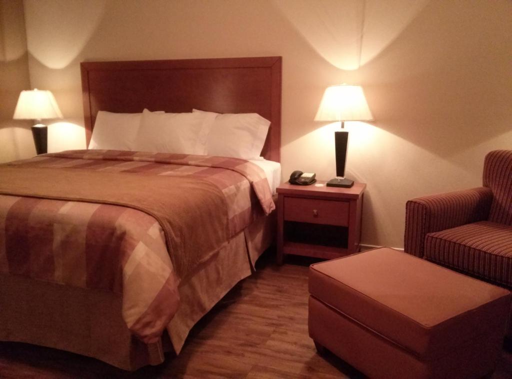 um quarto de hotel com uma cama e uma cadeira em FieldHouse Inn & Conference Center em Kenedy