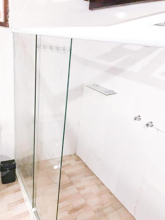 a glass shower in a white room with a wooden floor at Pipa Malbec in Petrópolis