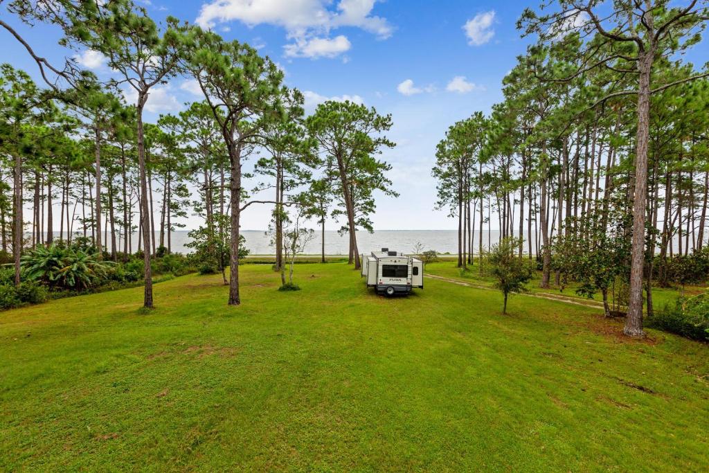 a camper parked in a field with trees at Pura Vida East Point with Bay View in Eastpoint