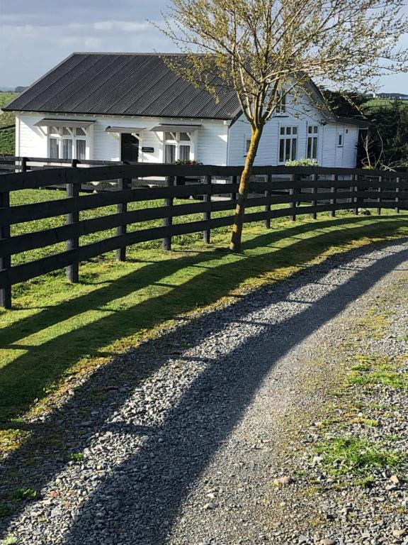 uma cerca em frente a uma casa branca em Ataahua Homestay em Feilding