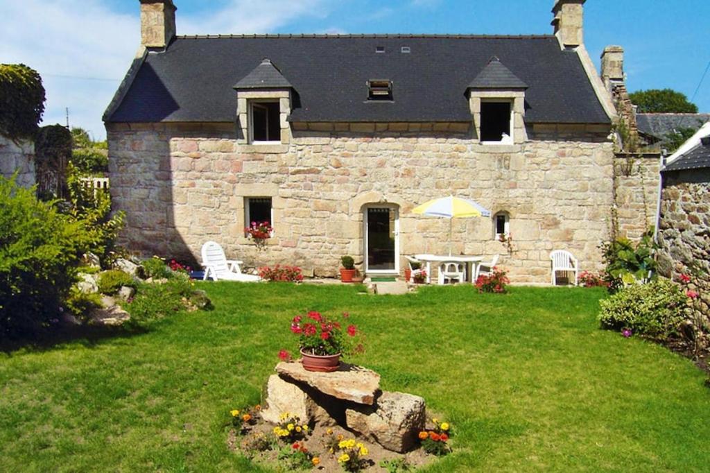 une maison en pierre avec une cour dotée d'une table et de fleurs dans l'établissement Cottage, Plouhinec, à Plouhinec