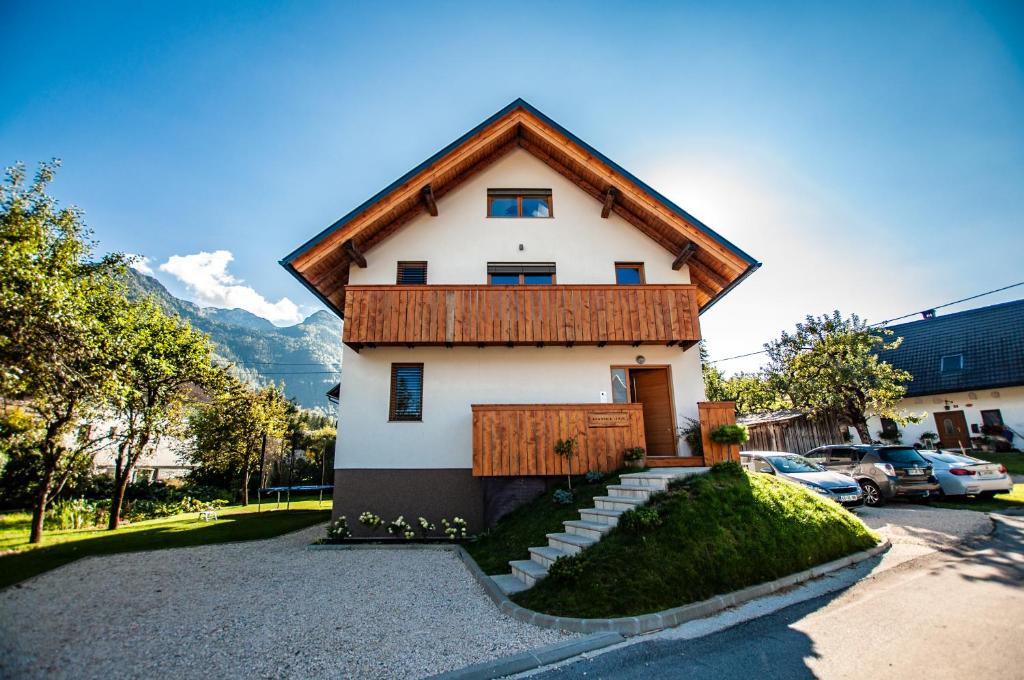 a white house with a wooden roof at Apartments Izvir in Bohinj