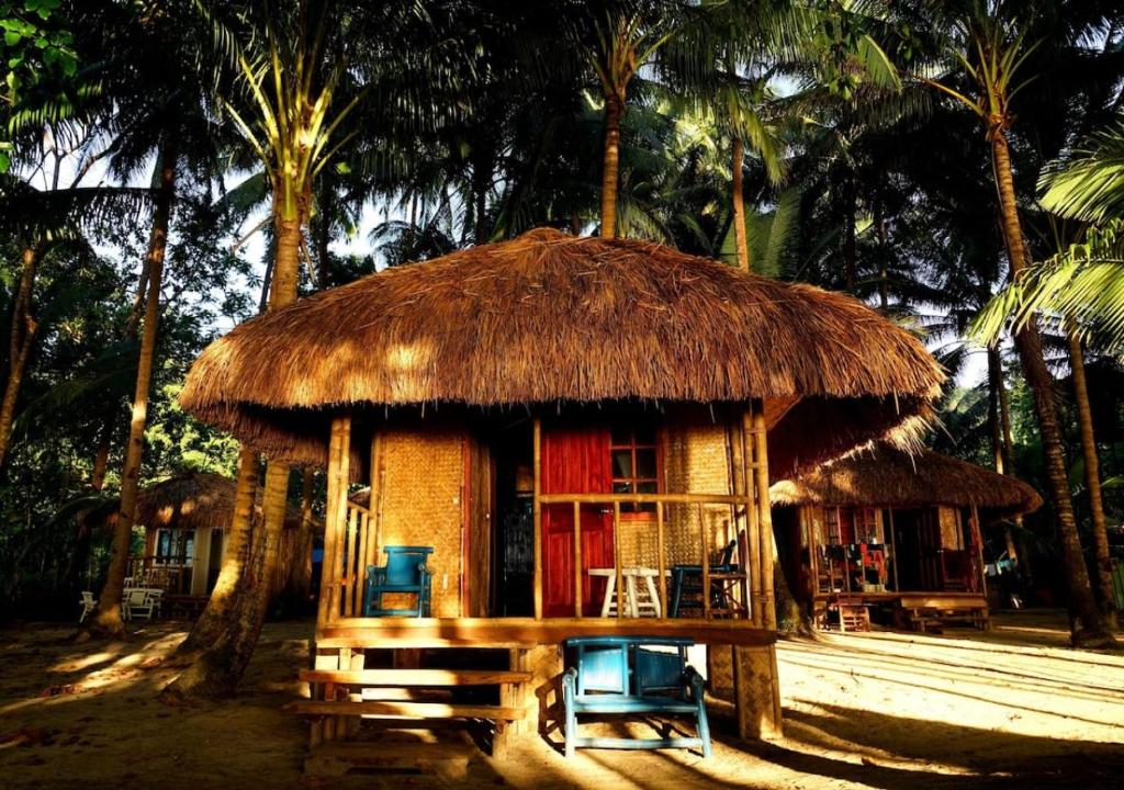 Cabaña pequeña con techo de paja, mesa y sillas en Arkadia Beach Resort by RedDoorz, en Sabang