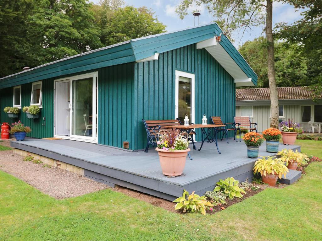 a green shed with a table and a patio at Meadow Lodge in Coldingham