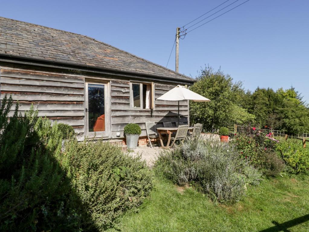 una casa con una mesa y una sombrilla en el patio en The Old Cart Shed en Fordingbridge