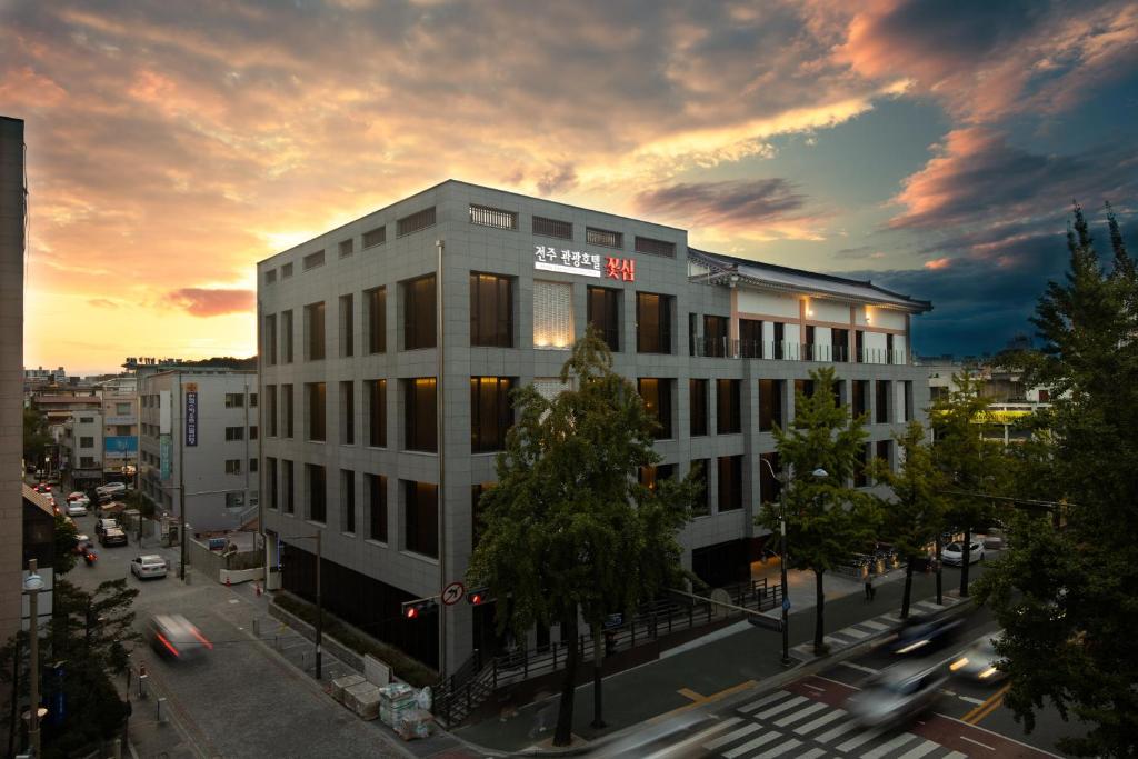 un edificio en una calle de la ciudad con una puesta de sol en Jeonju Tourist Hotel kkotsim en Jeonju