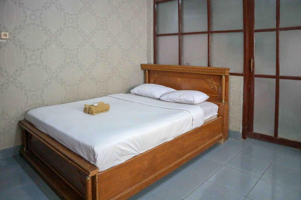 a bed with a brown purse sitting on top of it at Monjali Inn RedPartner near Tugu Yogyakarta in Jetis