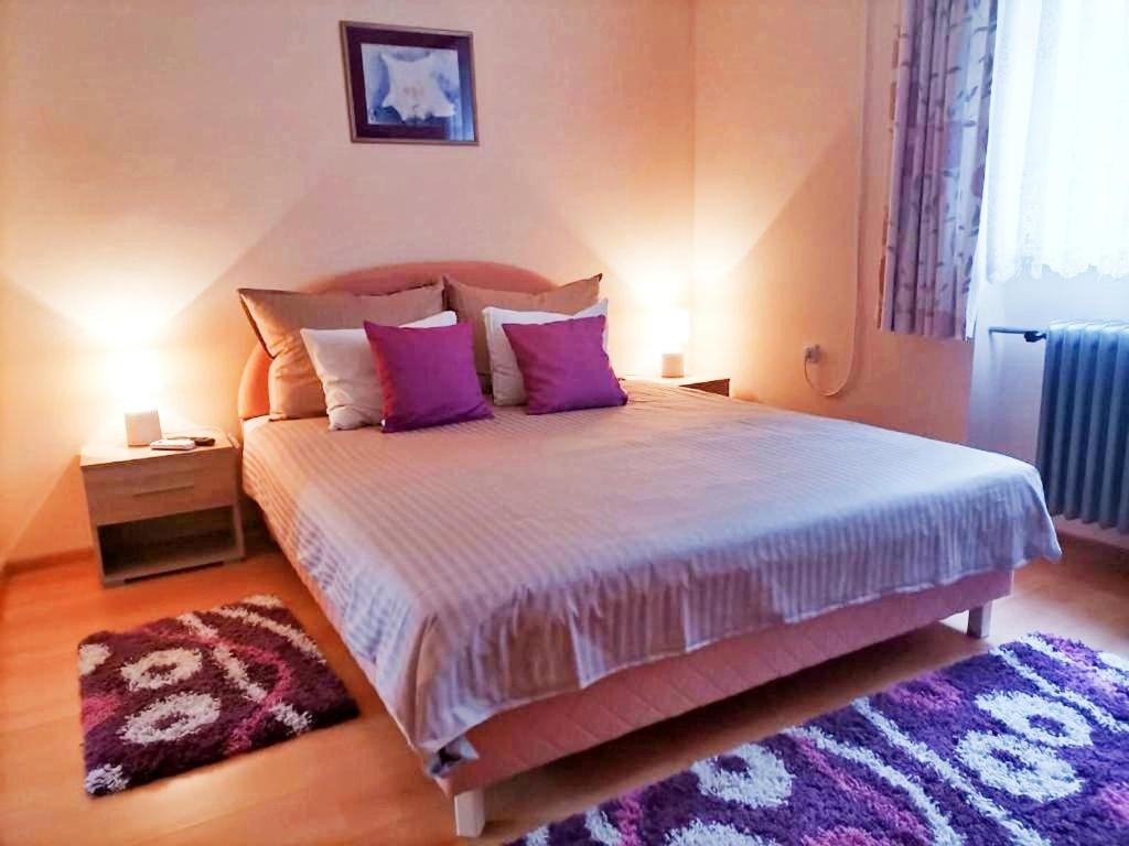 a bedroom with a large bed with purple pillows at Sandrea Studio Apartment in Subotica