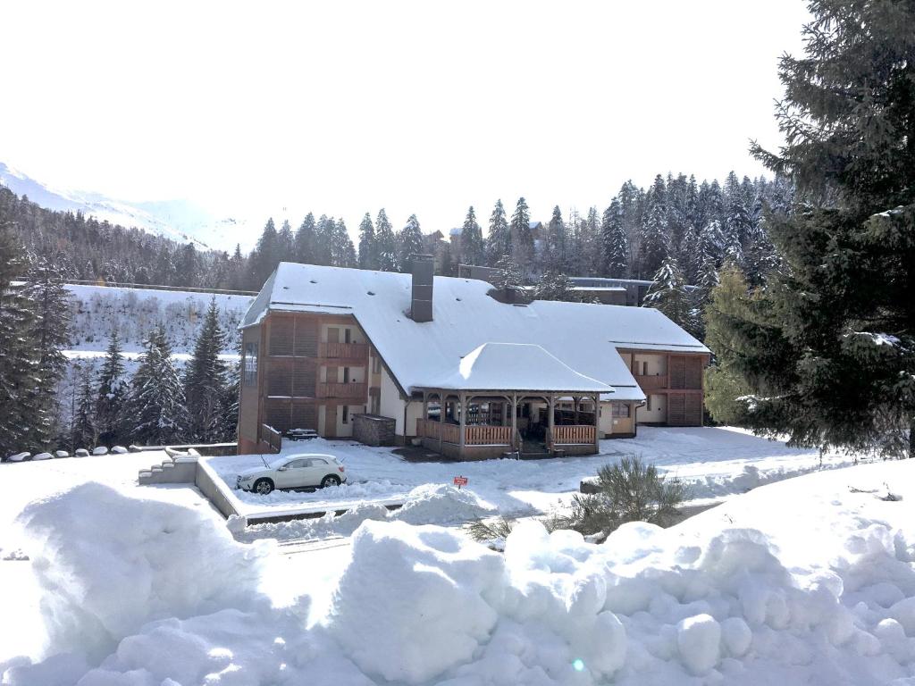 uma casa coberta de neve com um carro à frente em Résidence LE BEC DE L'AIGLE em Le Lioran