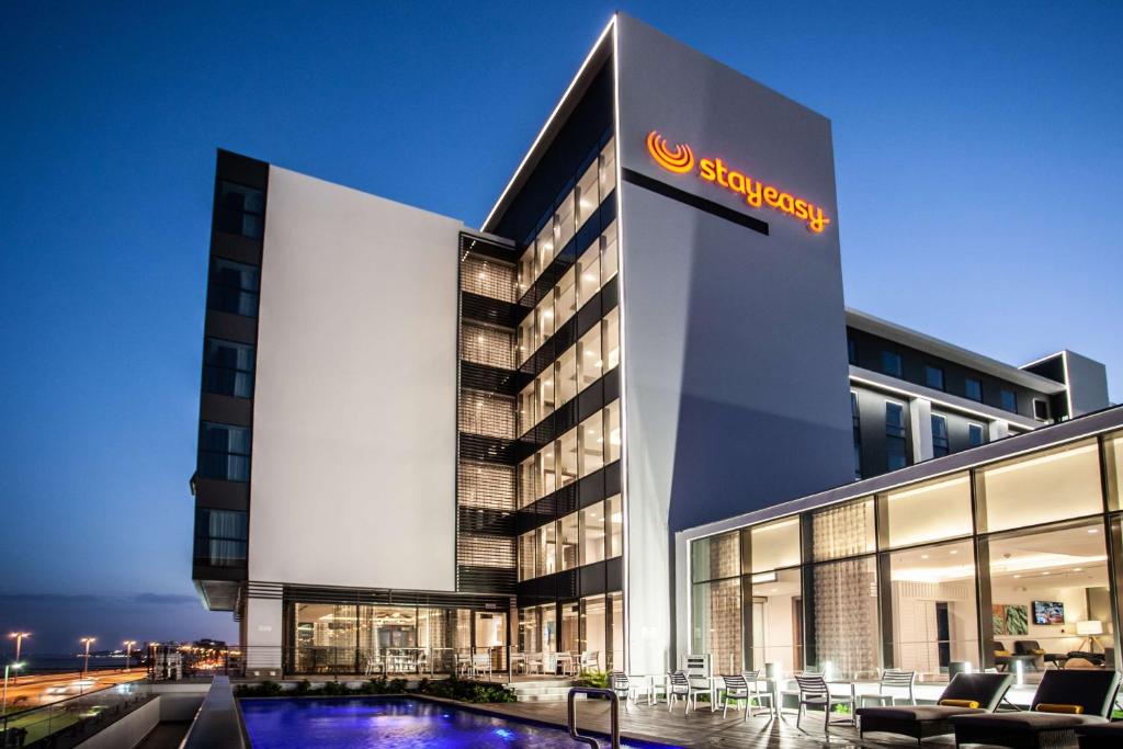 a hotel with a swimming pool in front of a building at StayEasy Maputo in Maputo