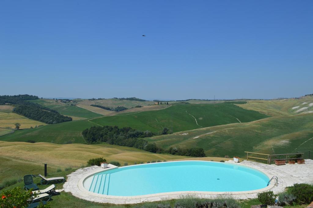uma piscina no meio de colinas verdes em Holiday apartment with swimming pool, strade bianche, swimming pool, view em Pievina