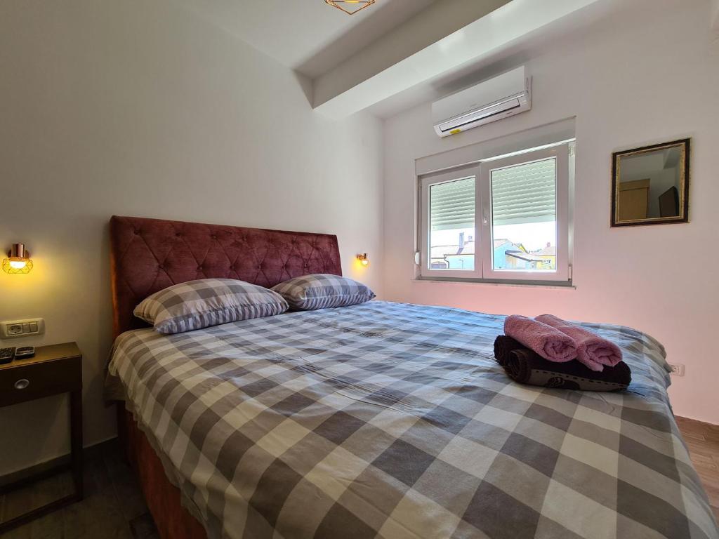 sypialnia z łóżkiem z kratkowaną narzutą i oknem w obiekcie House Plavi 2130 w Medulinie