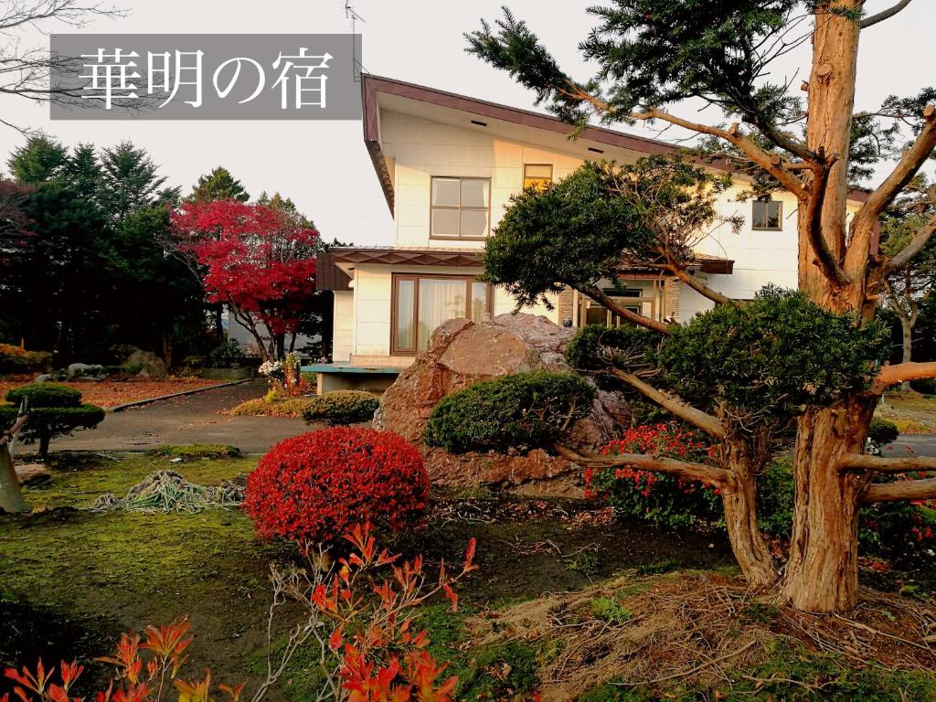 a house with a tree and flowers in front of it at 華明の宿 in Ebetsu
