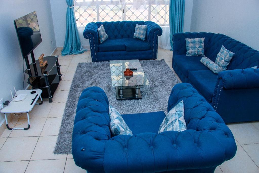 a living room with blue couches and a table at Lux Suites Greatwall Gardens Apartments in Machakos