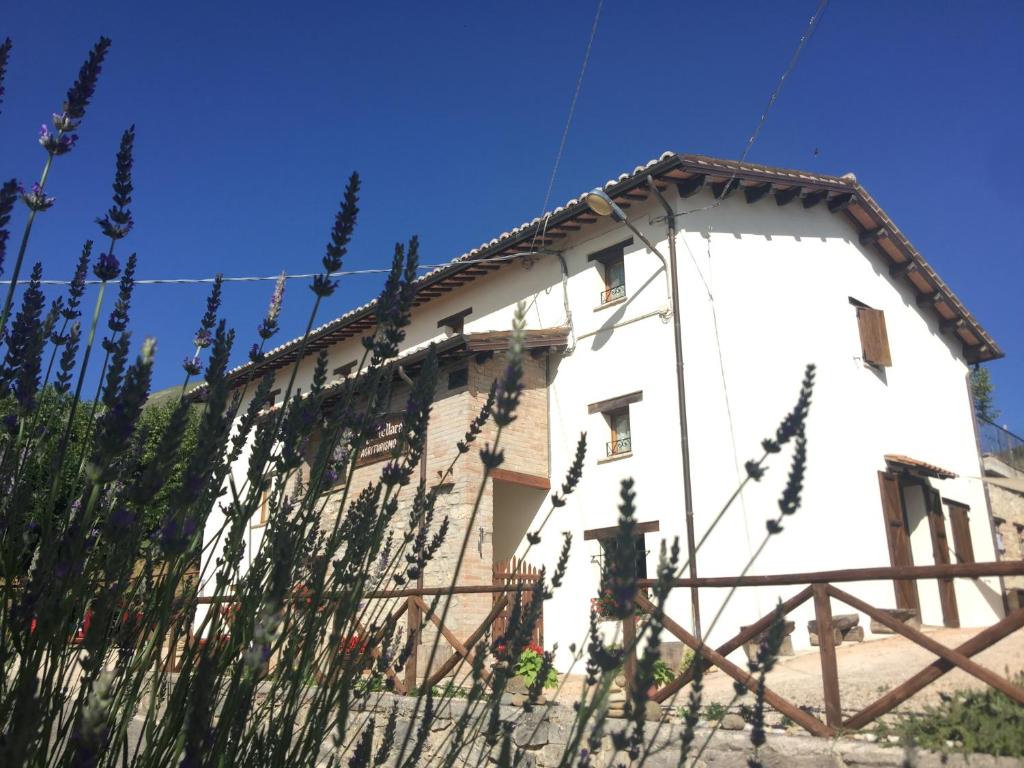 un bâtiment blanc avec une clôture devant lui dans l'établissement Agriturismo Le Castellare, à Montemonaco