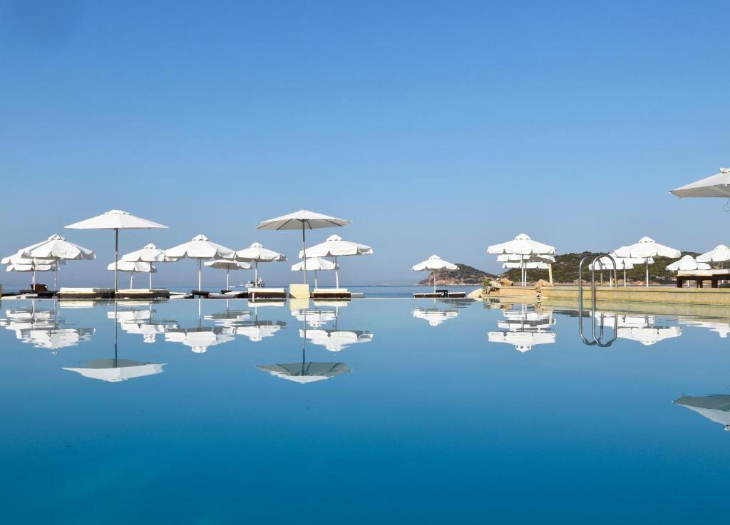 a pool of water with umbrellas on a beach at Plaza Resort in Anavyssos