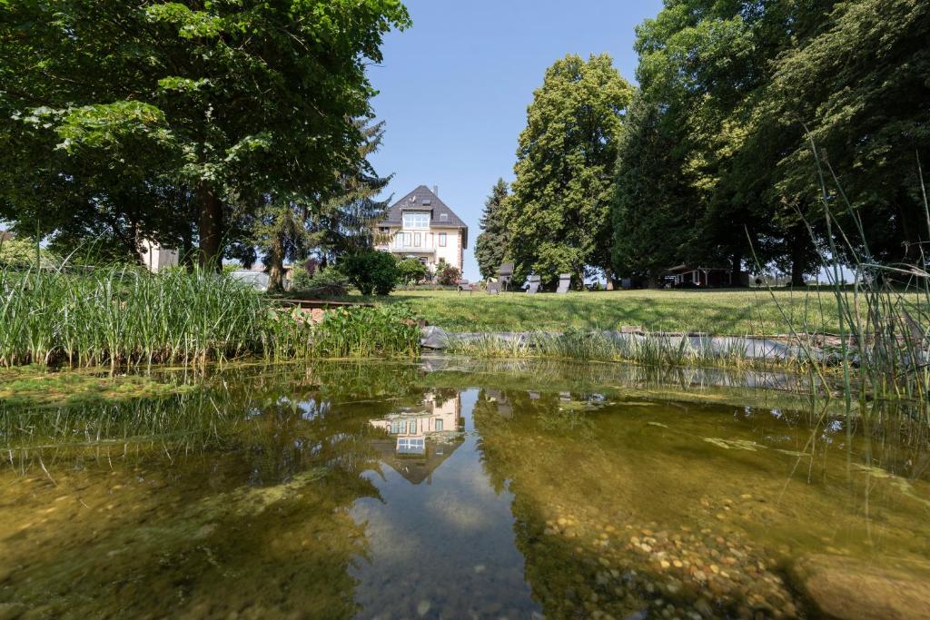a house is reflected in the water of a lake at Villa Geisenhof in Miltenberg