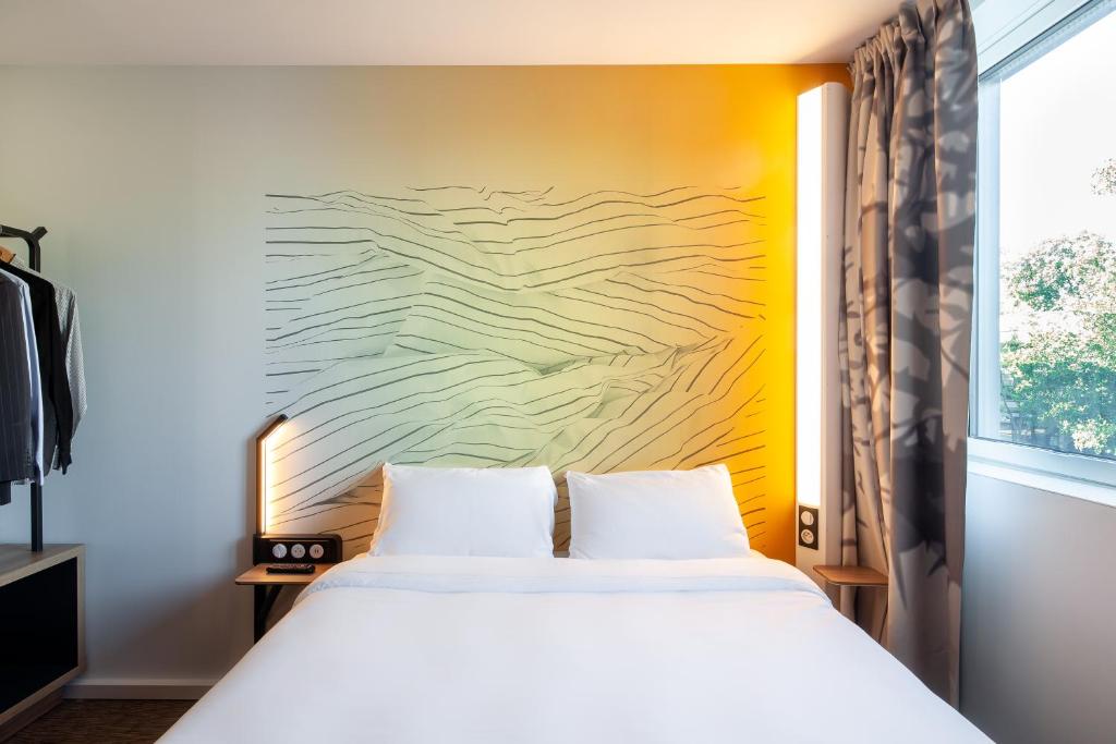 ボワ・ダルシーにあるB&B HOTEL Bois d'Arcy Saint Quentin en Yvelinesのベッドルーム1室(ベッド1台付)が備わります。壁には絵画が飾られています。