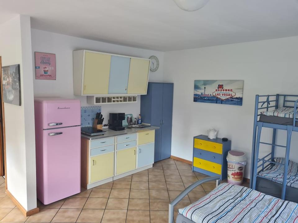 a kitchen with a pink refrigerator and yellow cabinets at Fifties Apartment Bechhofen in Bechhofen