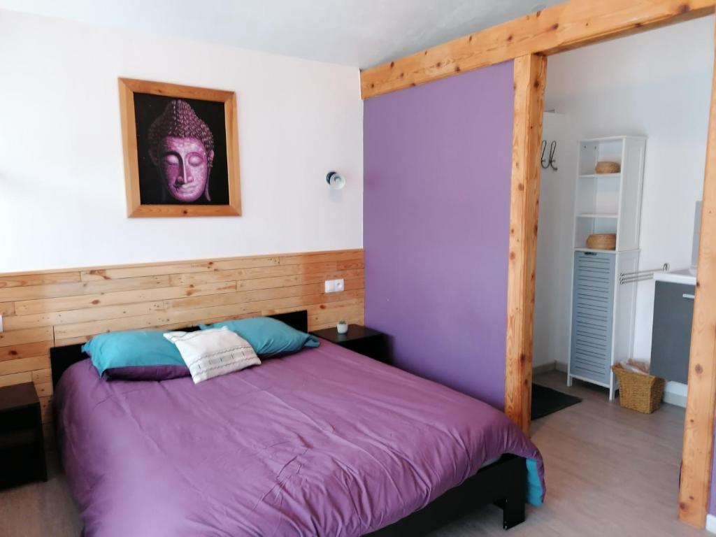 Saillans的住宿－Chambre avec jacuzzi privatif "le pêcher"，一间卧室配有一张带木制床头板的紫色床