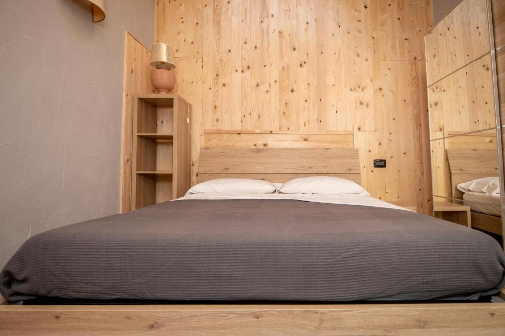 a bedroom with a bed with a wooden wall at Agriturismo La Cascina B&B in San Fedele Intelvi