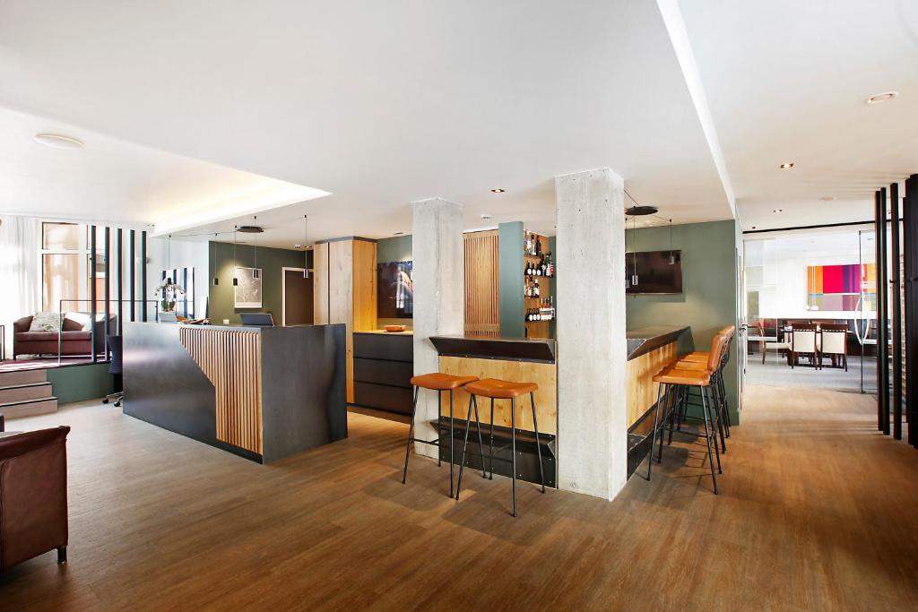 uma cozinha e sala de estar com um bar com bancos em Hotel am Jakobsmarkt em Nuremberga