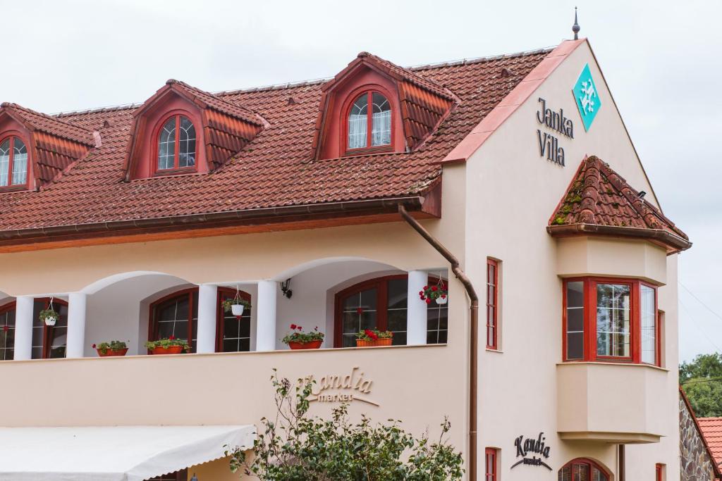 un bâtiment blanc avec des fenêtres rouges et un toit dans l'établissement Janka Villa, à Călugăreni