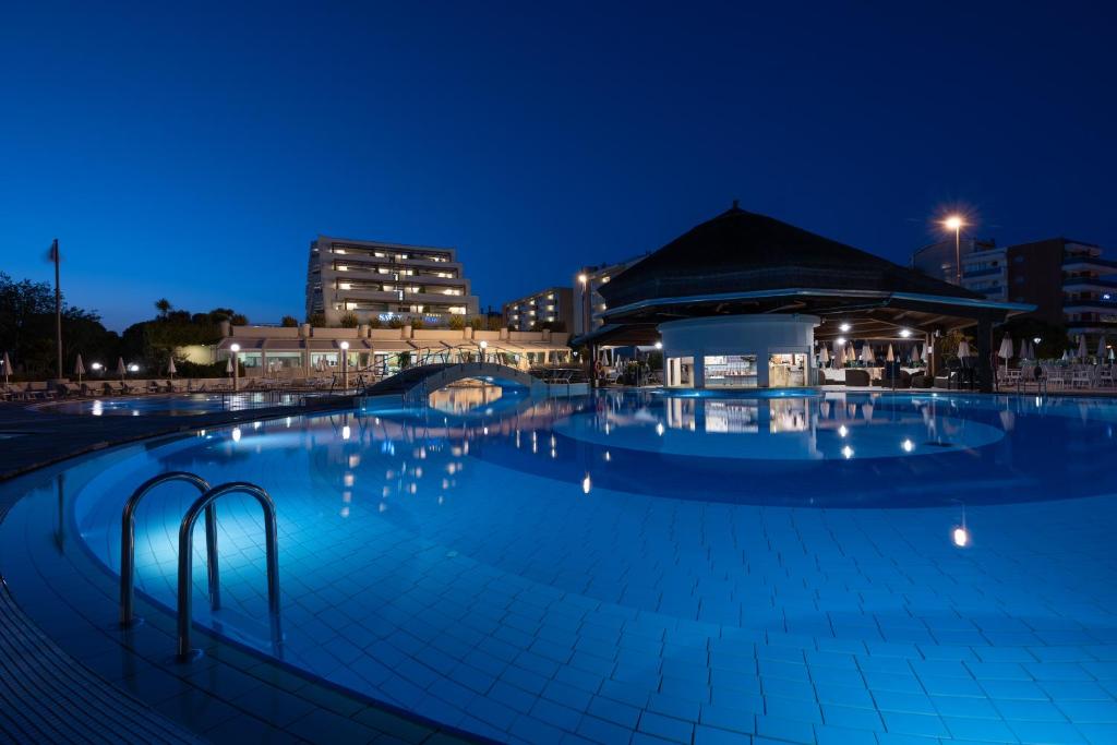 ein Schwimmbad in der Nacht mit einem Gebäude im Hintergrund in der Unterkunft Savoy Beach Hotel & Thermal Spa in Bibione