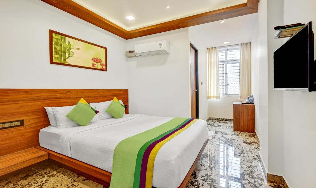 a bedroom with a large bed and a television at Itsy By Treebo - Shrey'S Inn Mallandur Road in Chikmagalūr