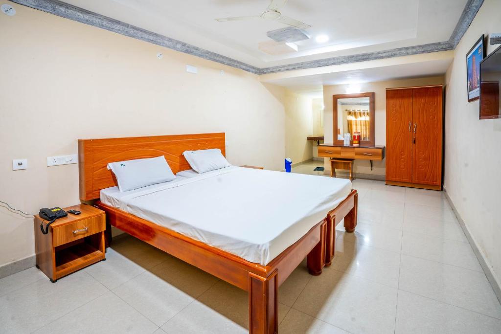 a bedroom with a large bed and a desk at Hotel TamilNadu, Hosur in Hosūr