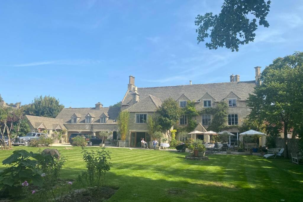 a large house with a lawn in front of it at The Old Manor Coach House in Cirencester
