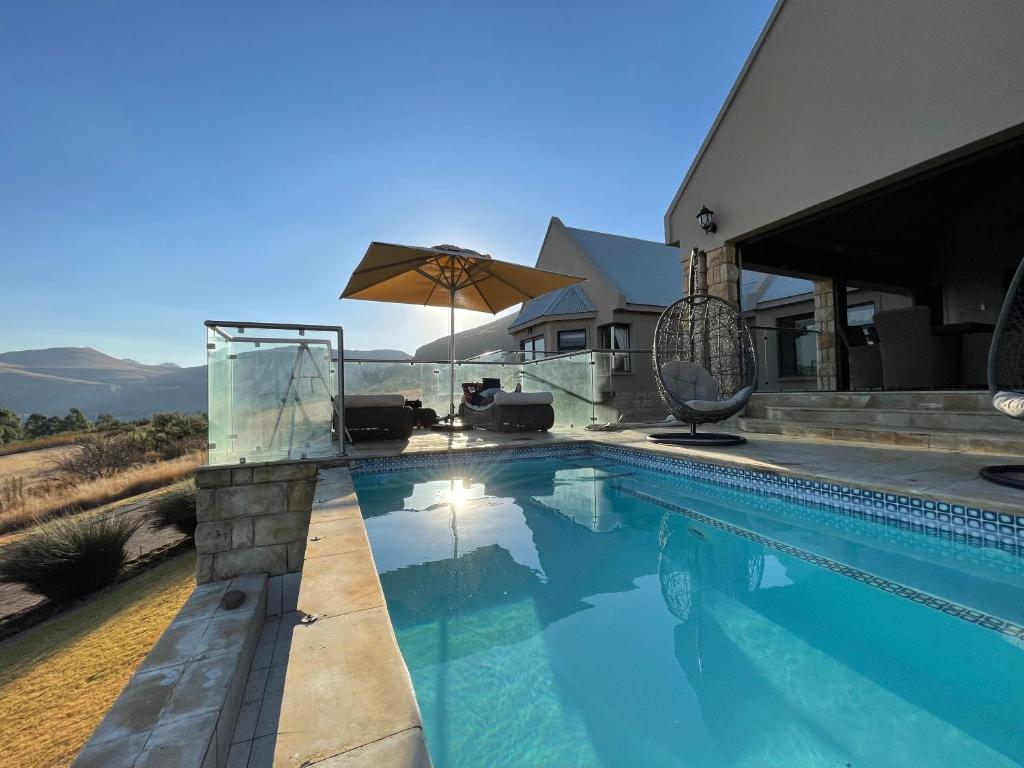 a swimming pool with an umbrella next to a house at Clarens Grand Villa in Clarens
