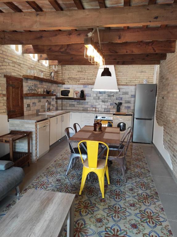 Casa Rural MESTRE في ديلتيبري: مطبخ بطاولة خشبية وكراسي صفراء