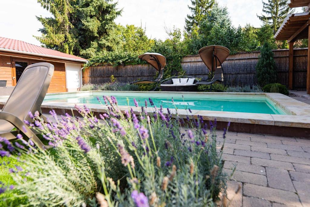 a swimming pool in a garden with purple flowers at Allium Apartment in Mak&oacute;
