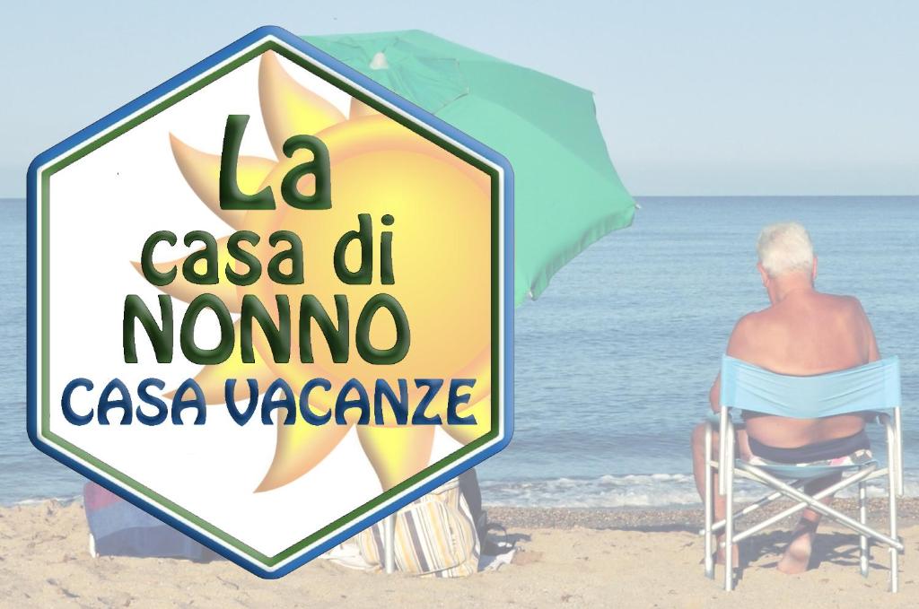 un homme assis sur une chaise sous un parasol sur la plage dans l'établissement La casa di Nonno, à Iglesias