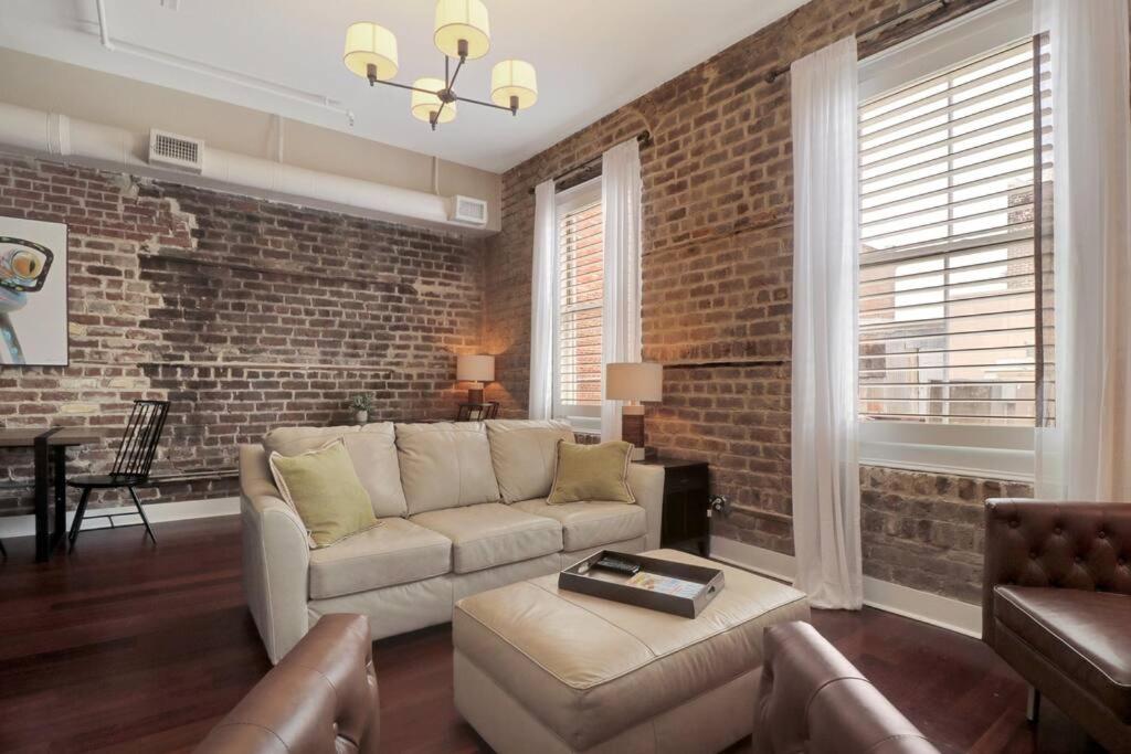 ein Wohnzimmer mit Sofa und Ziegelwand in der Unterkunft Downtown Loft- Steps away from Plant Riverside! in Savannah