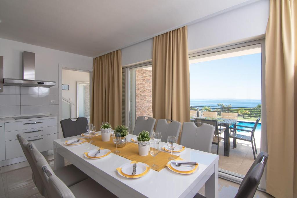 kuchnia i jadalnia z białym stołem i krzesłami w obiekcie Villas Royal I with Private Pool w Novalji