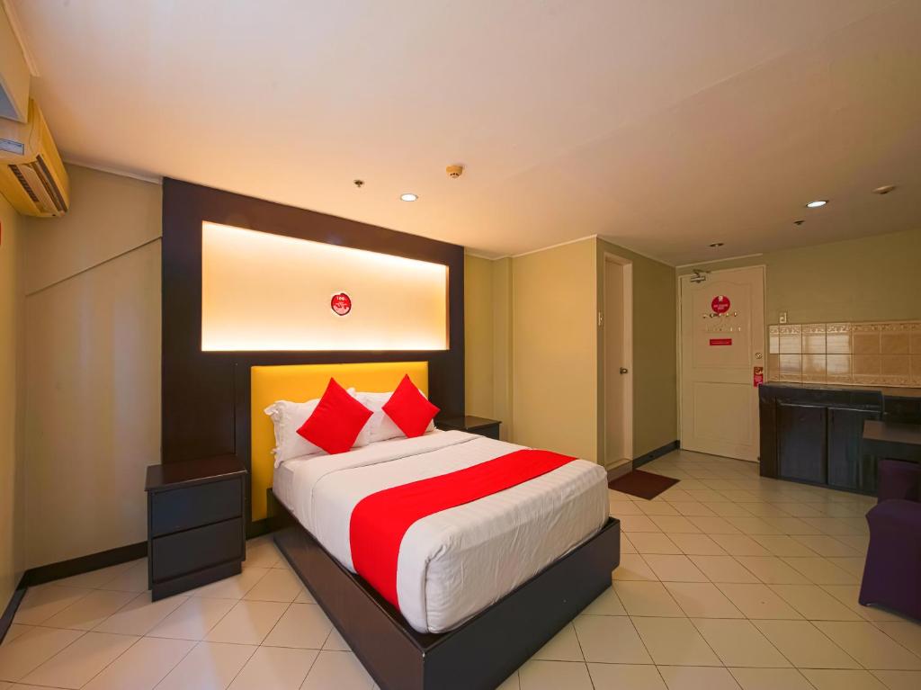 um quarto com uma cama grande e almofadas vermelhas em OYO 115 Northridge Mansions em Manilla