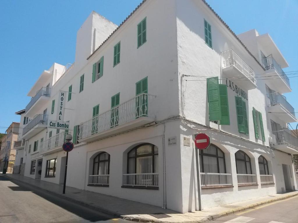 un edificio blanco con persianas verdes en una calle en Hostal Cas Bombu, en Cala Ratjada