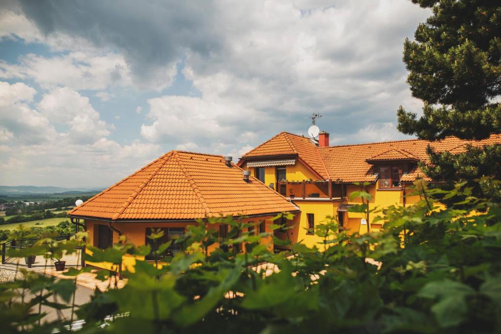 a yellow house with orange roofs on a hill at Apartmány Na Vyhlídce in Paseka