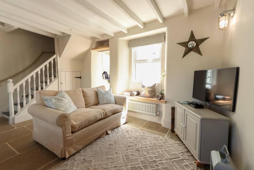 a living room with a couch and a flat screen tv at North View cottage. Shaldon village. in Shaldon
