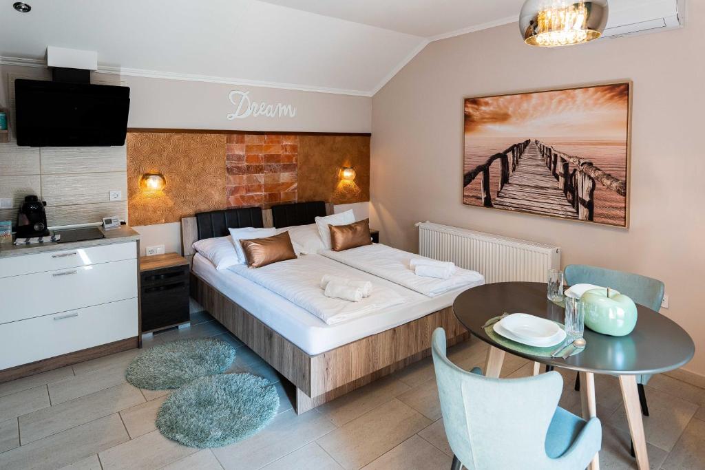 a bedroom with a bed and a table and a kitchen at Allium Apartment in Makó