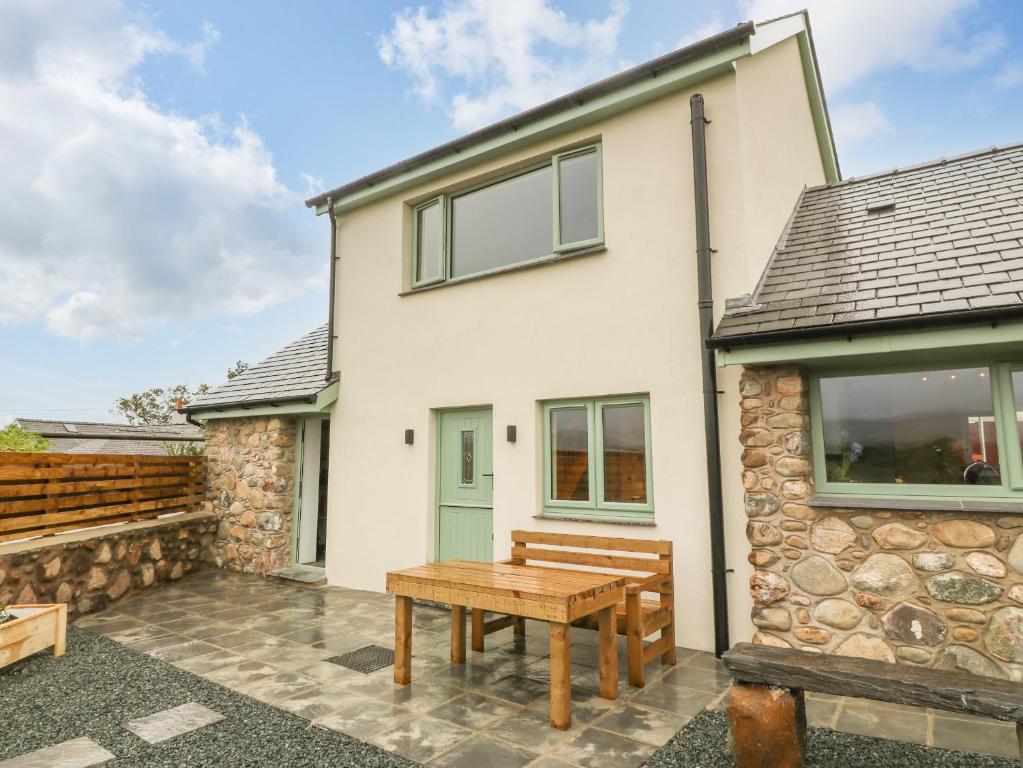 a house with a wooden table in front of it at Ty Gwair The Hayloft in Caernarfon