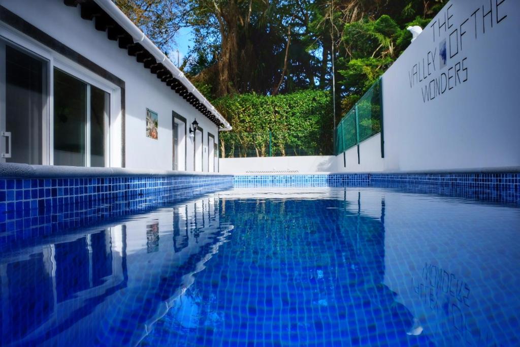 a blue swimming pool next to a white building at Vale dos Encantos in Furnas