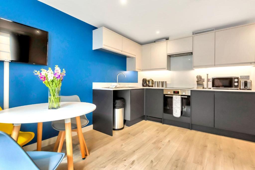 a kitchen with a white table and a blue wall at St Pauls Apartments in Cheltenham