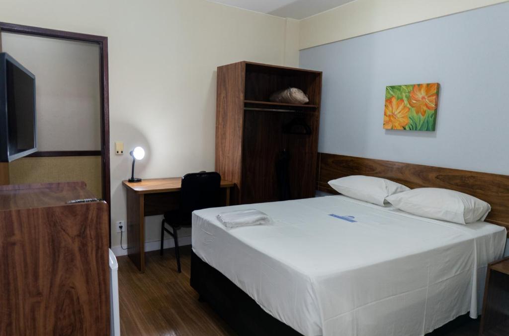 a bedroom with a bed and a desk and a television at Nobile Plaza Hotel in Taguatinga