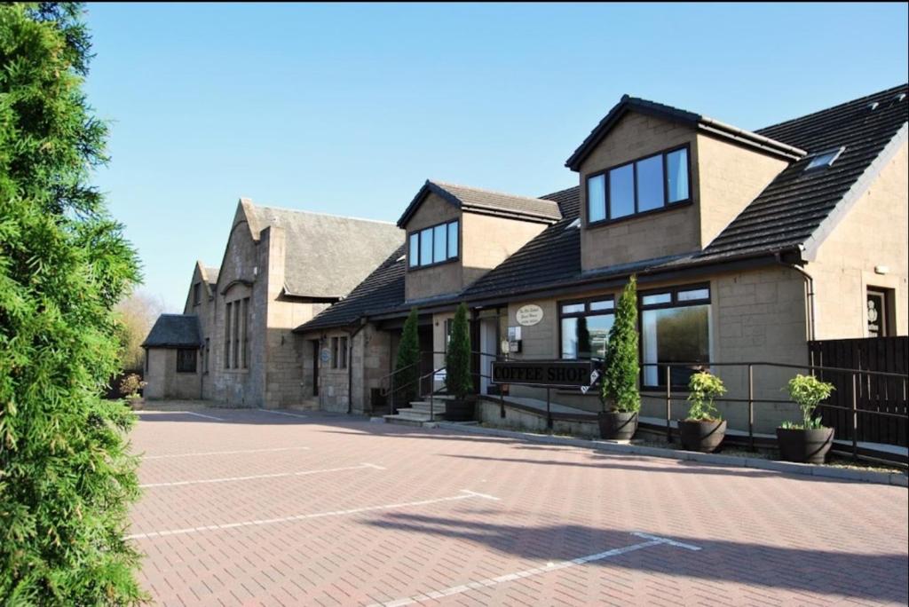 una casa con una pista de tenis delante en The Old Schoolhouse Hotel en Larkhall