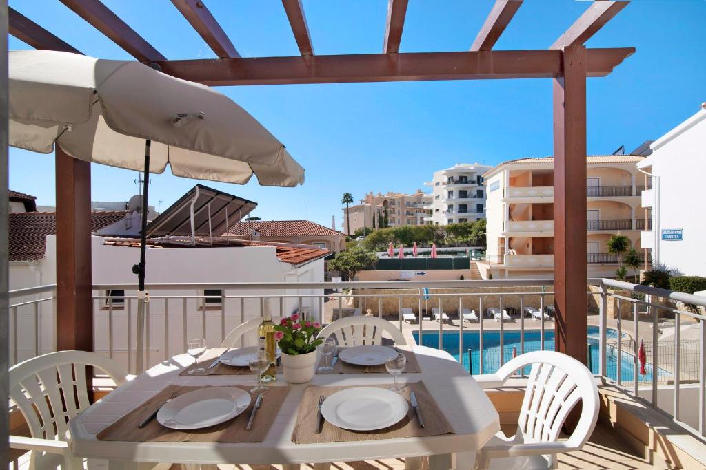 a white table with chairs and an umbrella on a balcony at Apartamento Água Brisa in Albufeira