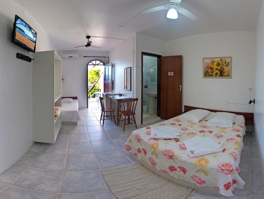 ein Schlafzimmer mit einem großen Bett und ein Esszimmer in der Unterkunft Lobo Hotel in Garopaba